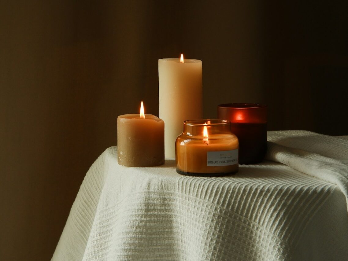 three lit candles sitting on a white table cloth